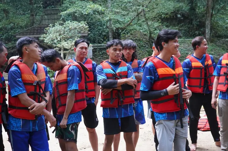 Peserta rafting memakai rompi pelampung di tepi sungai